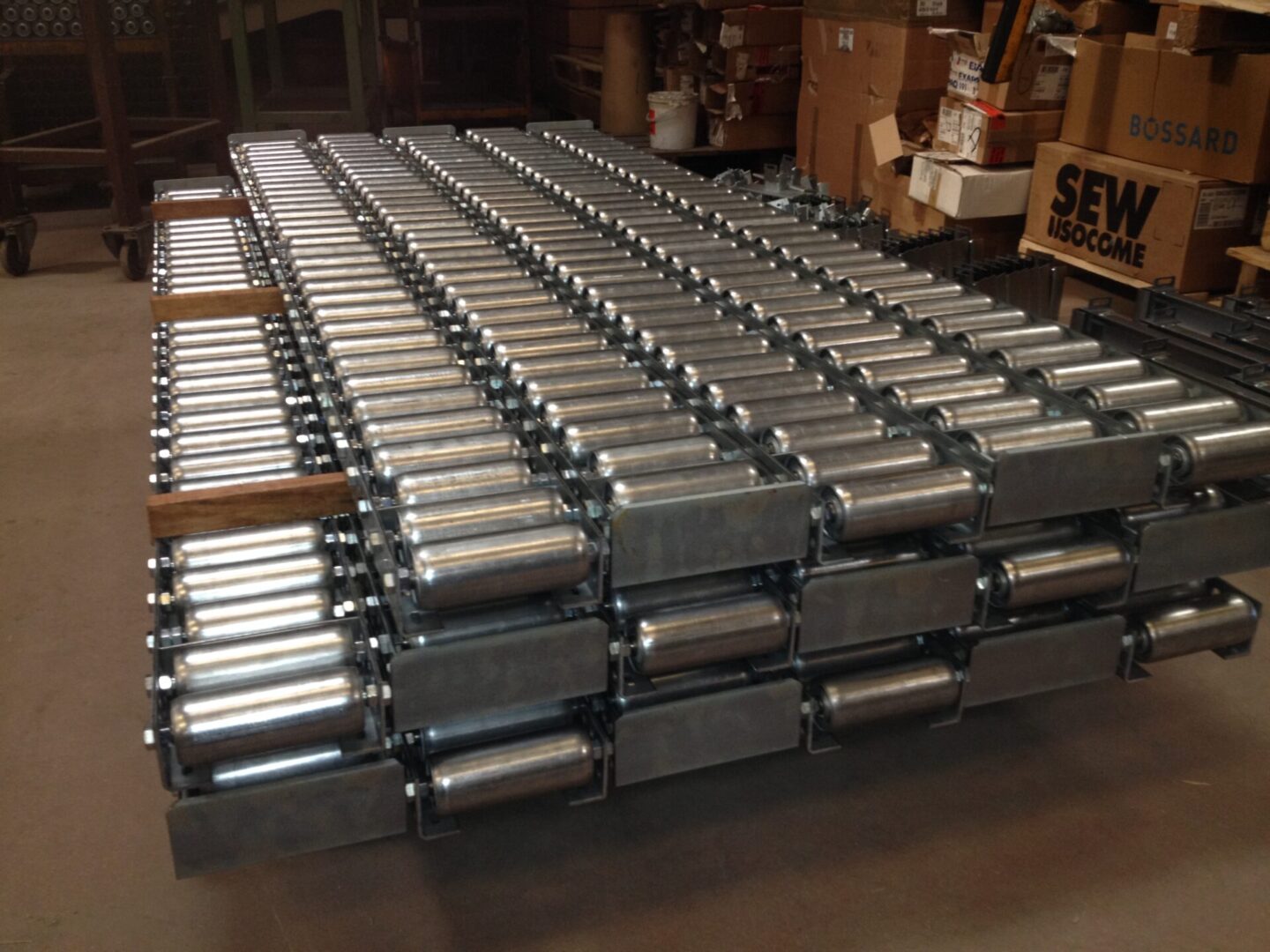 Ensemble de rails à galets au sol empilés dans un entrepôt, prêts pour une installation ou une utilisation.